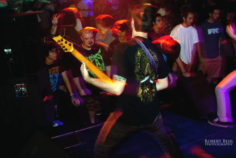 a man with an electric guitar standing in front of another guy holding his head up