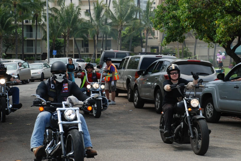 motorcycles are going down a street with people in front of some buildings