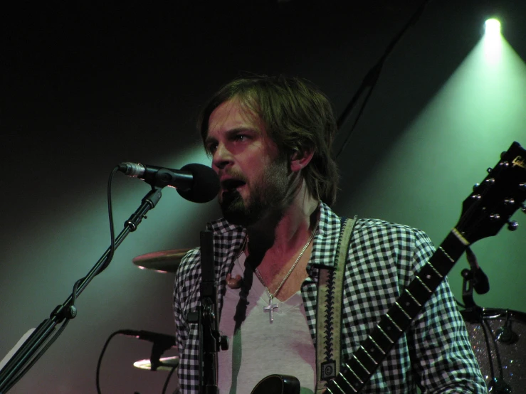 the man is playing guitar on stage in front of a microphone