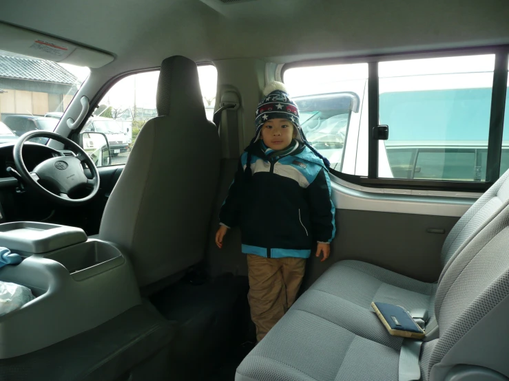 a child stands next to the seat in his car