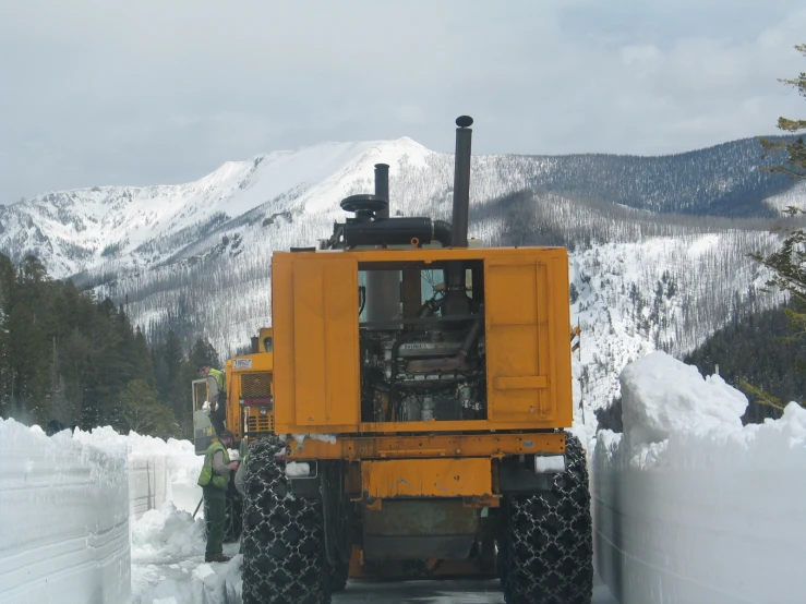 snow - packed hills surrounding a tractor like vehicle on a road