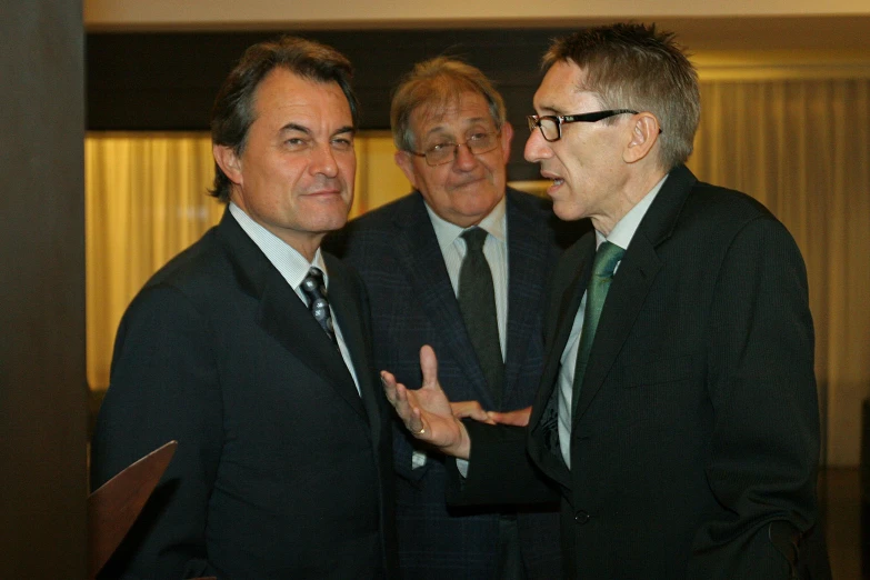 two men in suits speak while the others look on