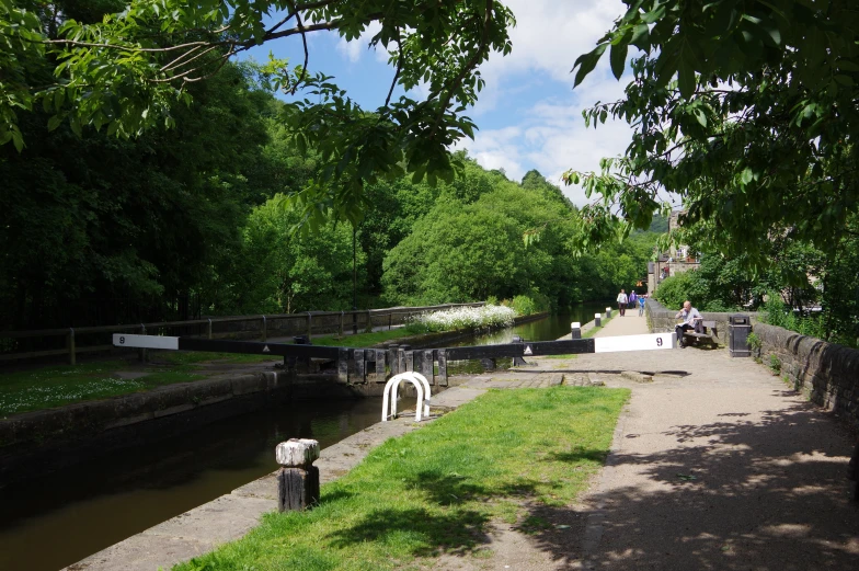 a canal is shown with a bench, grass and boats