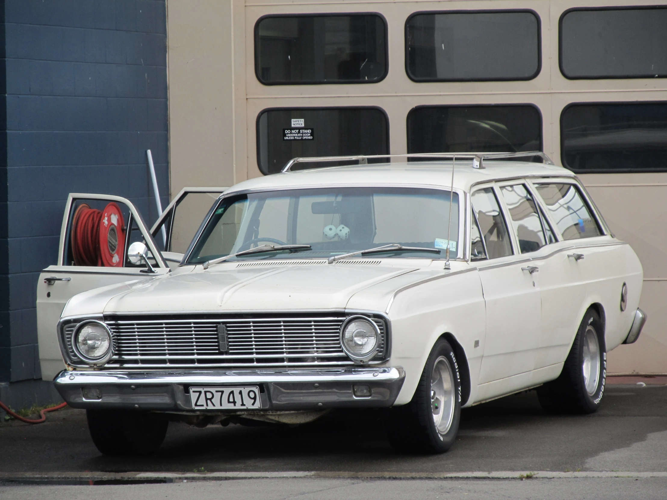 old station wagon parked beside a gas pump on the side of the street