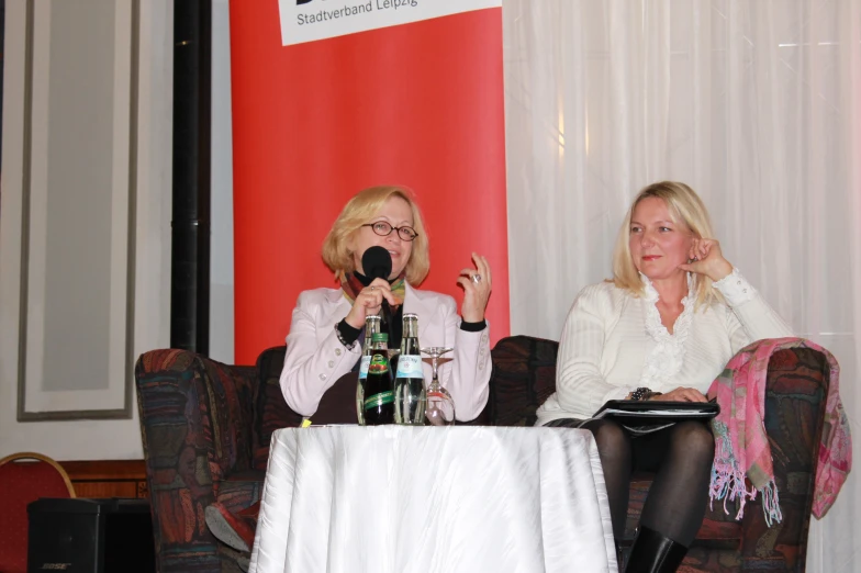 two women sitting on chairs at a microphone