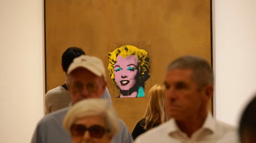many people are looking at some paintings with woman's face in it