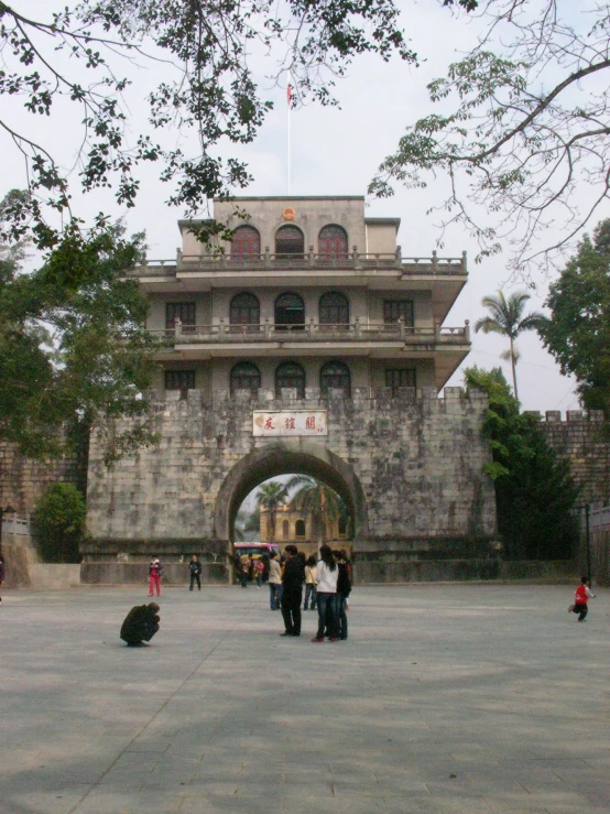 tourists walking past a stone arch with an archway in the background