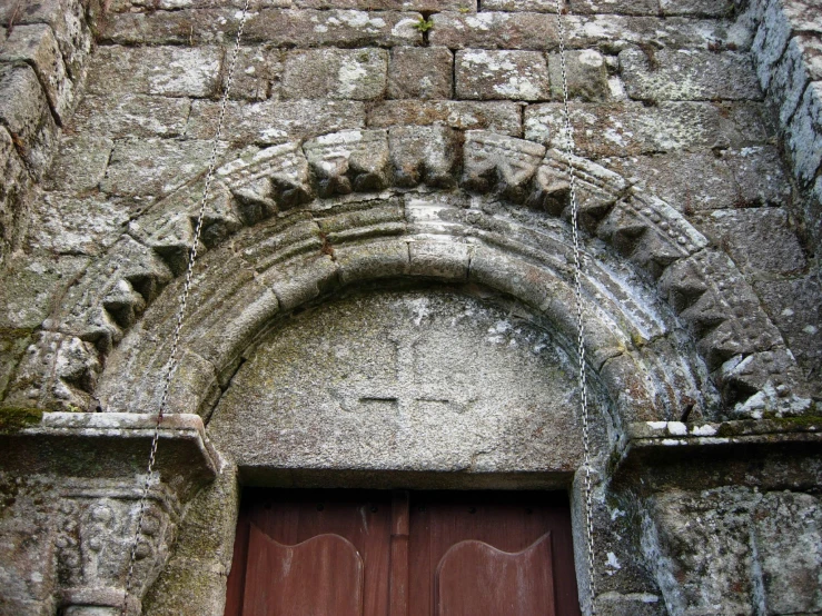 an old stone building with two wooden doors and a red door handle