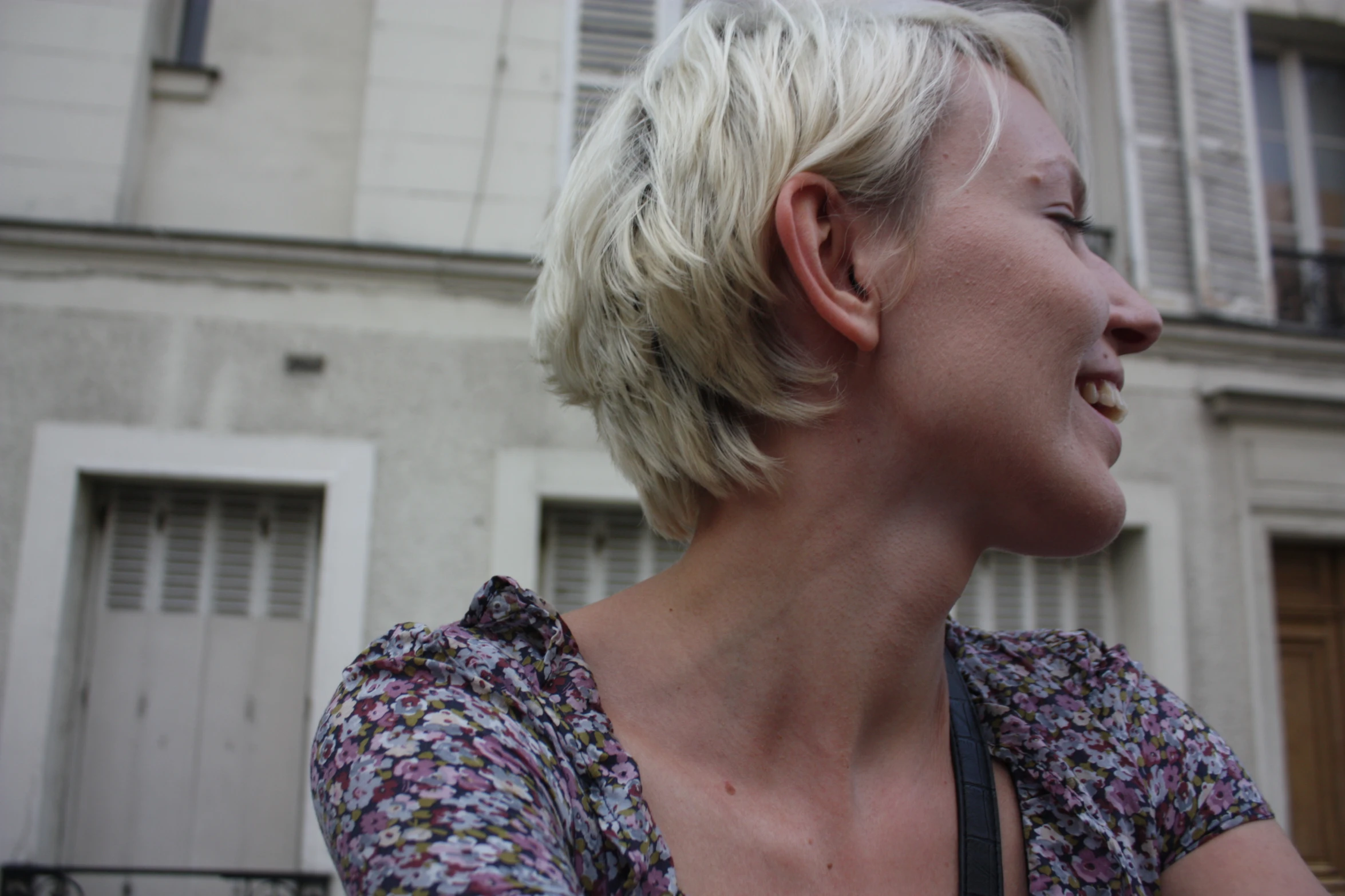 blonde woman with shoulder - length cut smiling outside a building