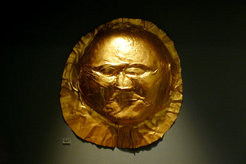 a gold plate is displayed with a face cut out