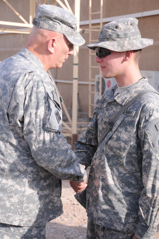 two soldiers shaking hands while standing on a dirt ground