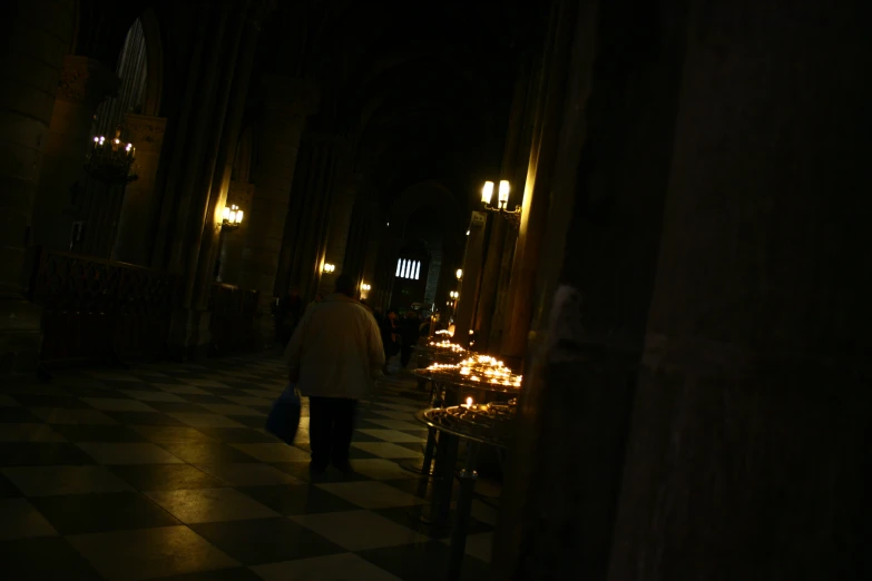 a man with some candles in his hand walking down the aisle