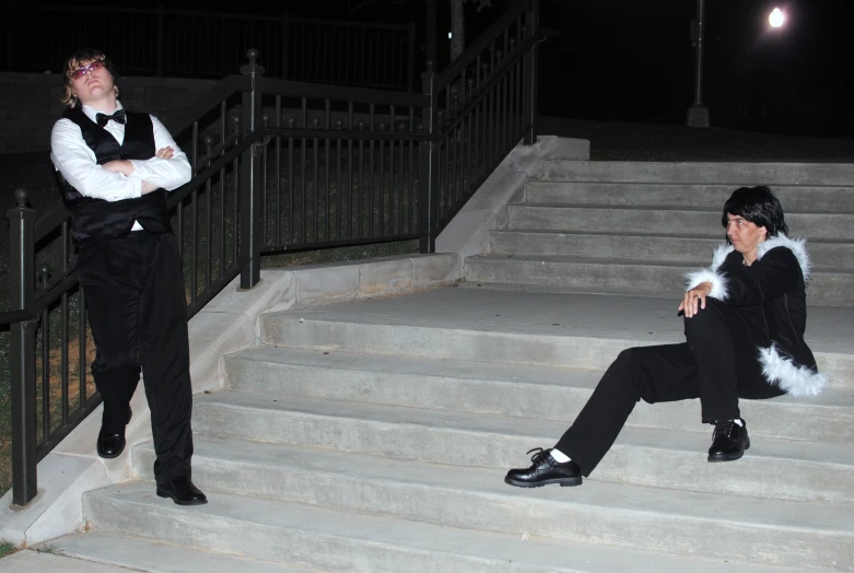 two men in costumes sitting on the steps of a stairway