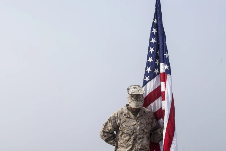 a soldier is holding an american flag while standing with his back turned