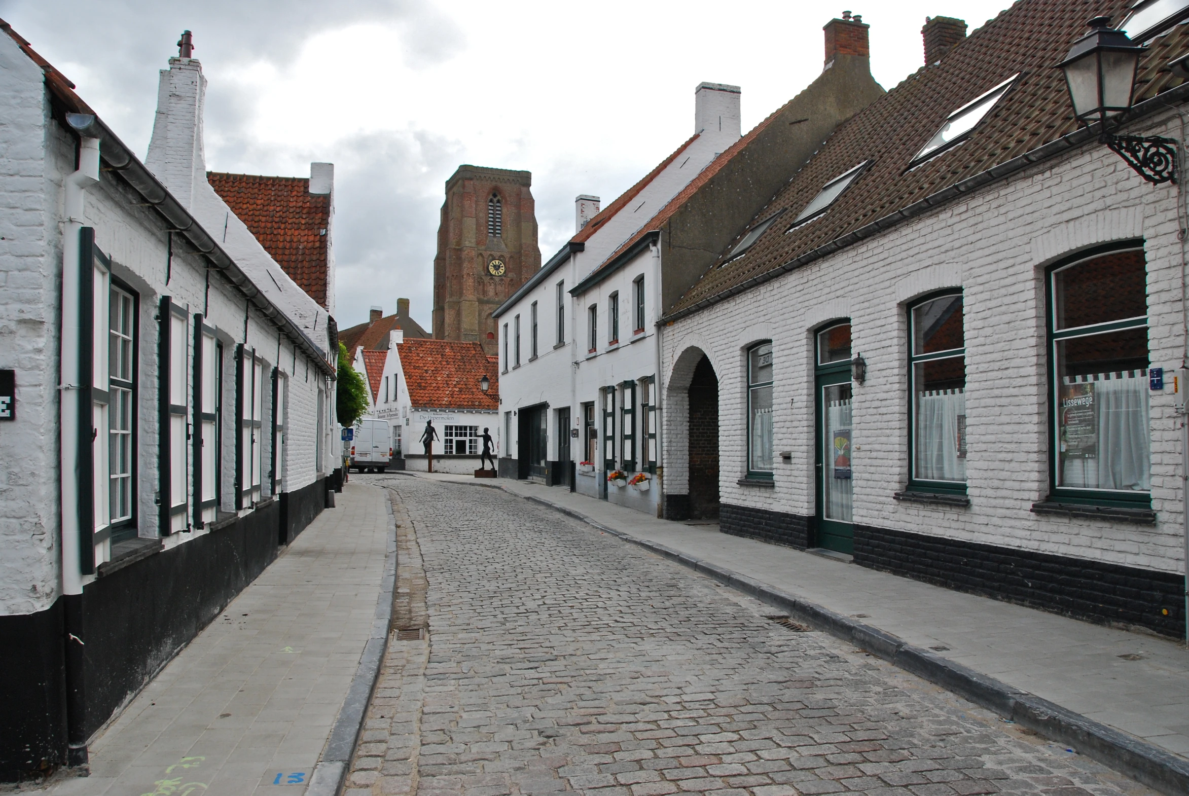 an empty brick road next to several white buildings