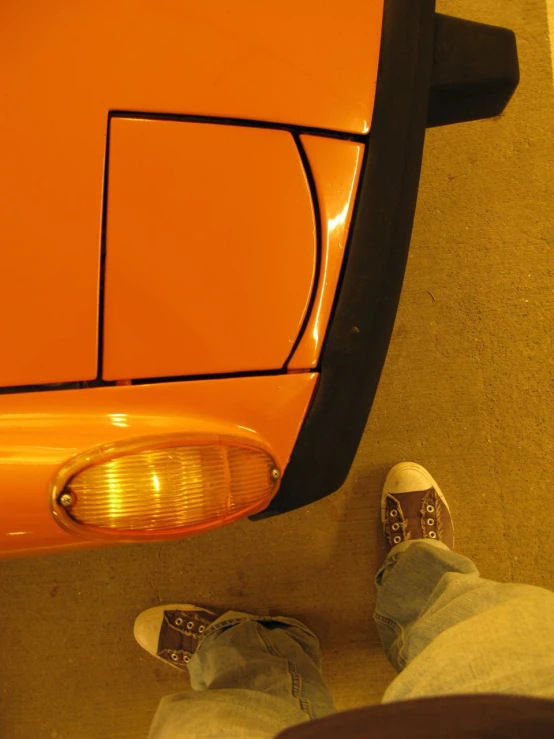 a person is standing under a bright orange vehicle