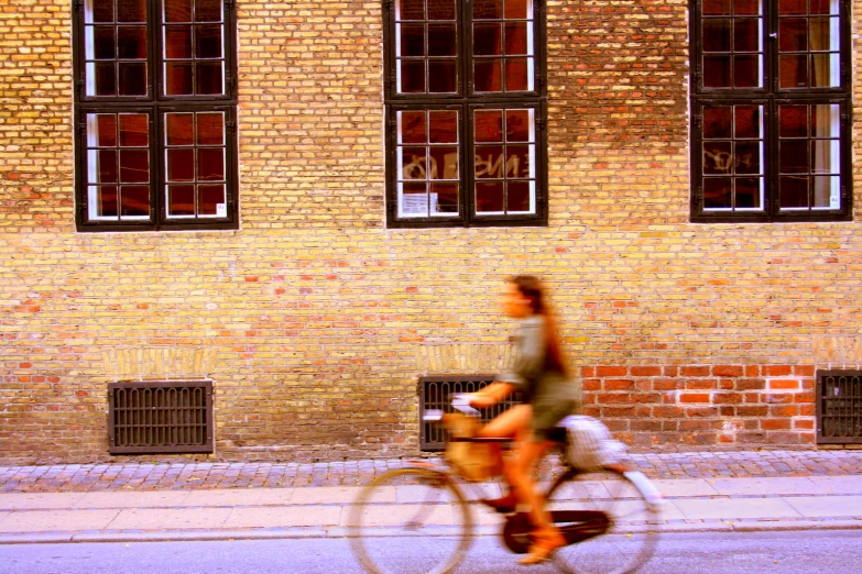 the woman is riding a bike in front of a brick building