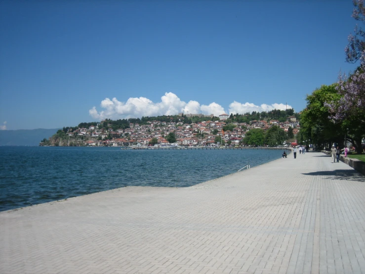 a street next to a body of water with a city in the distance