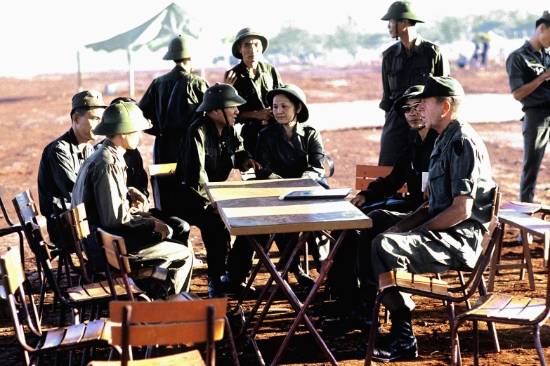 a group of soldiers are sitting at an old fashioned table