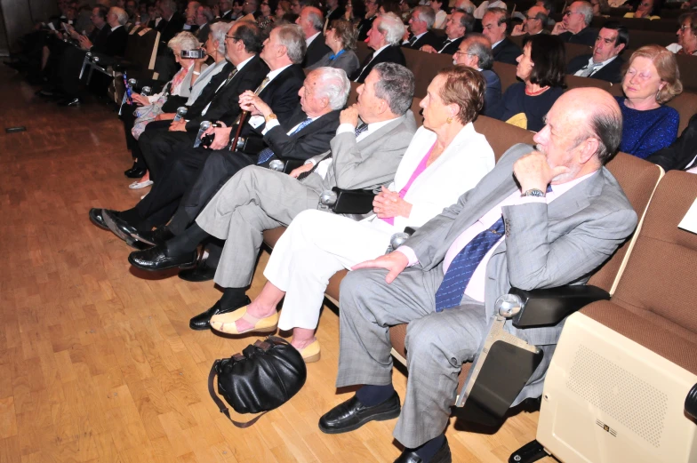 an audience is in the foreground as a man speaks on his cell phone