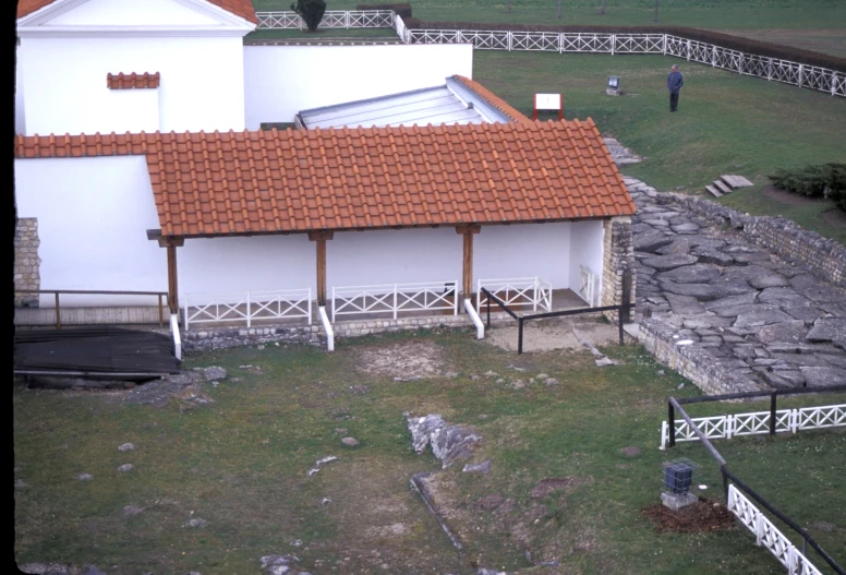 an old building with tiled roof next to a large field