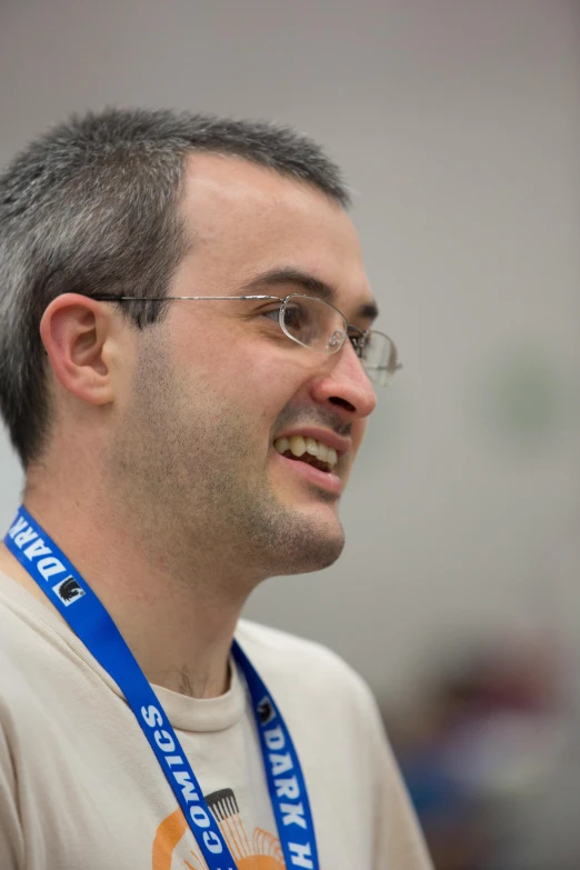 a smiling man with glasses and a lanyard around his neck