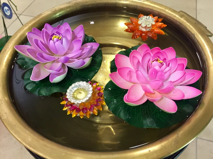 some pink flowers floating in water on a ss bowl