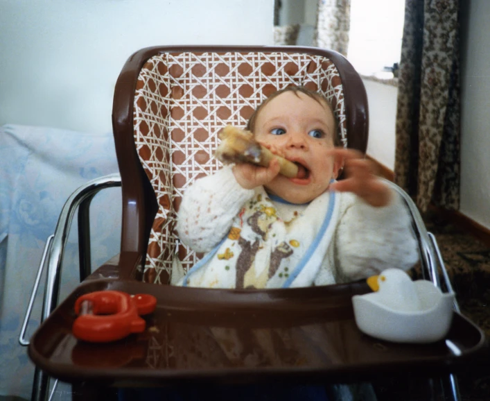 a baby sitting in a high chair eating food