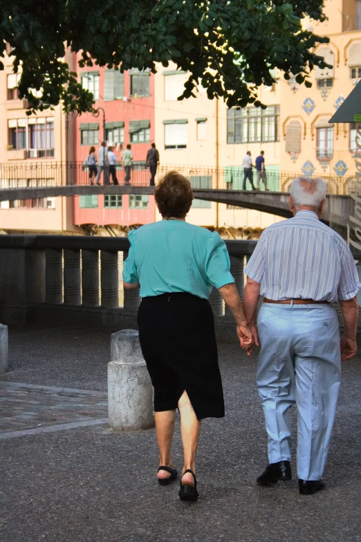 elderly couple walking on sidewalk towards urban area