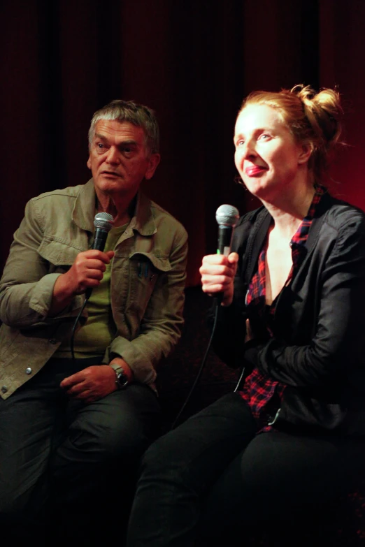 a woman holding a microphone while sitting next to a man