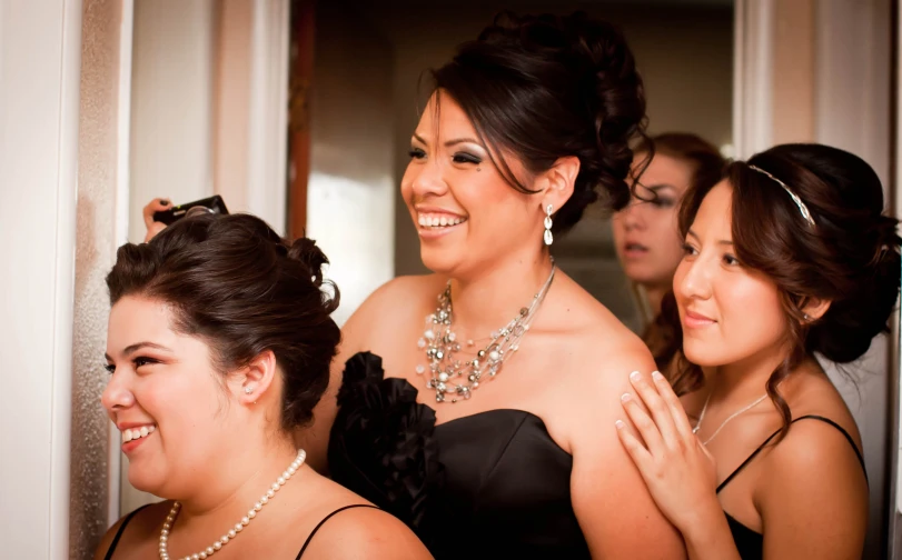 two woman smiling in front of a mirror with other women