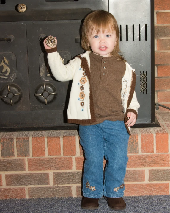 a little boy standing by a stove with his hand in the pocket