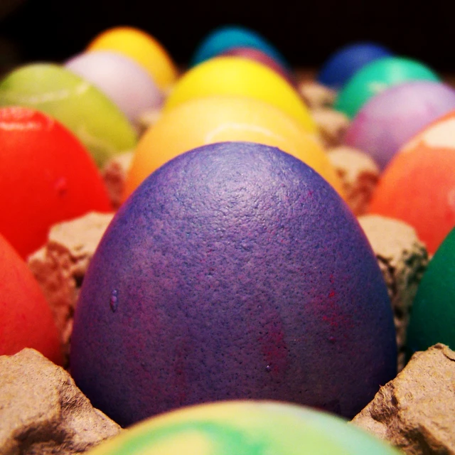 some colored eggs in a bowl filled with smaller eggs