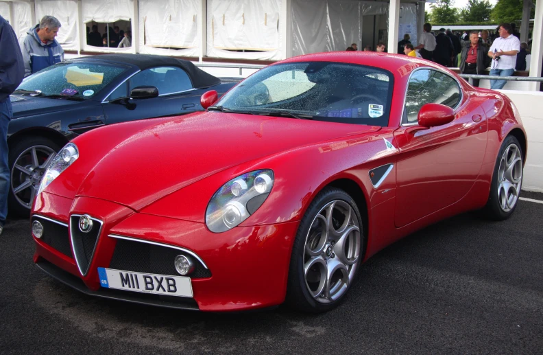 a red alfa car sitting on the side of a road