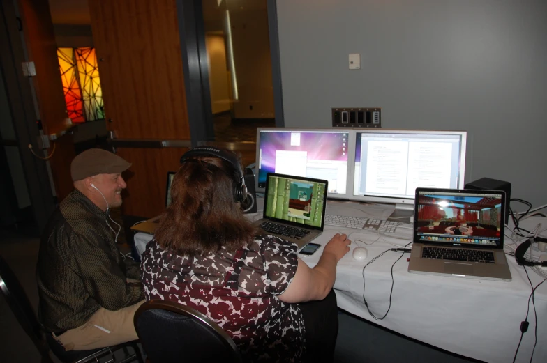 three people using laptops and computers to work on their tasks