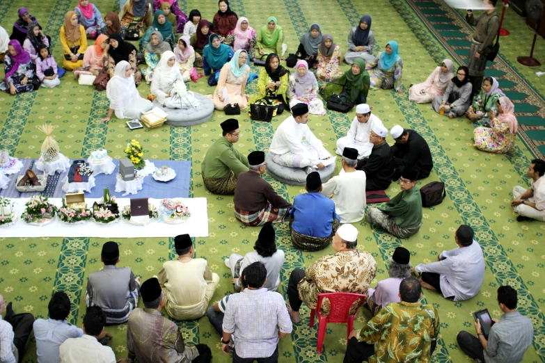 several people sitting on a rug in front of each other