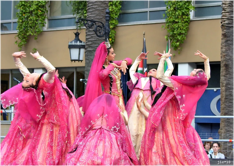 women in pink dresses perform during a parade