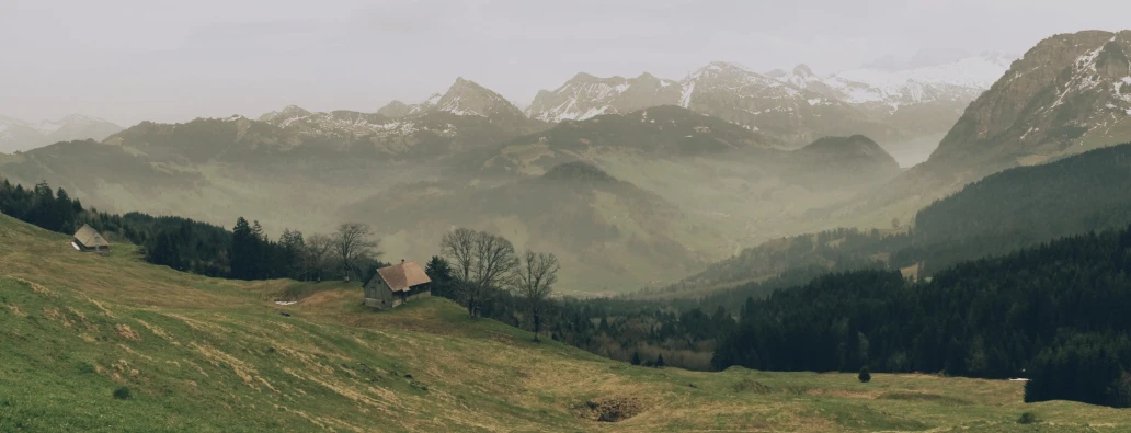 fog covers mountains with sp green grass and houses