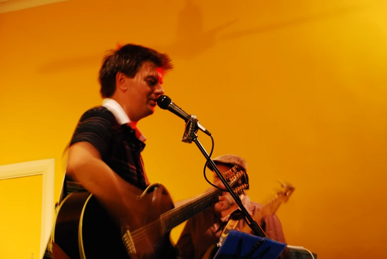 a man holding a guitar and singing into a microphone