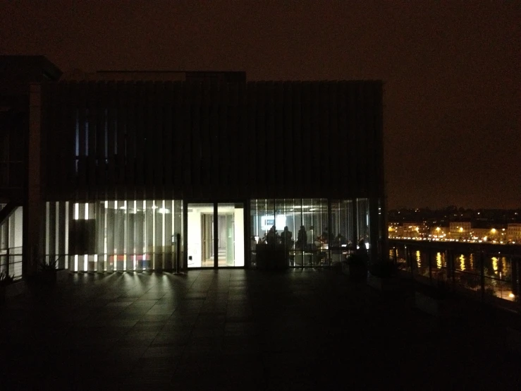 a room is lit up in the dark while people stand at doors