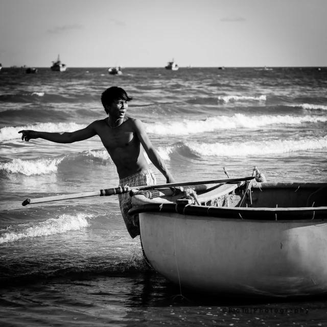 the man stands next to the boat and water