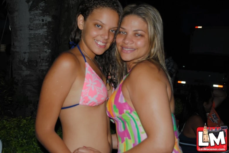 two girls in bikinis are smiling and hugging