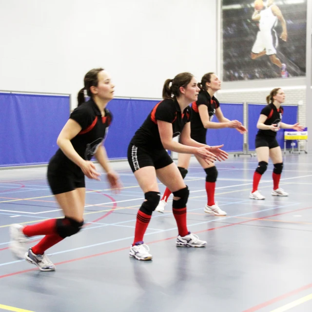 some women in black and red uniforms playing volleyball