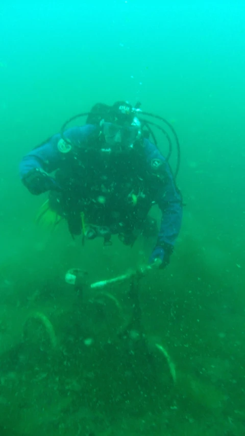 scuba diver in deep water with various debris around