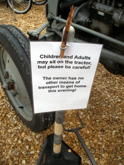 a sign next to a wheel on some dirt
