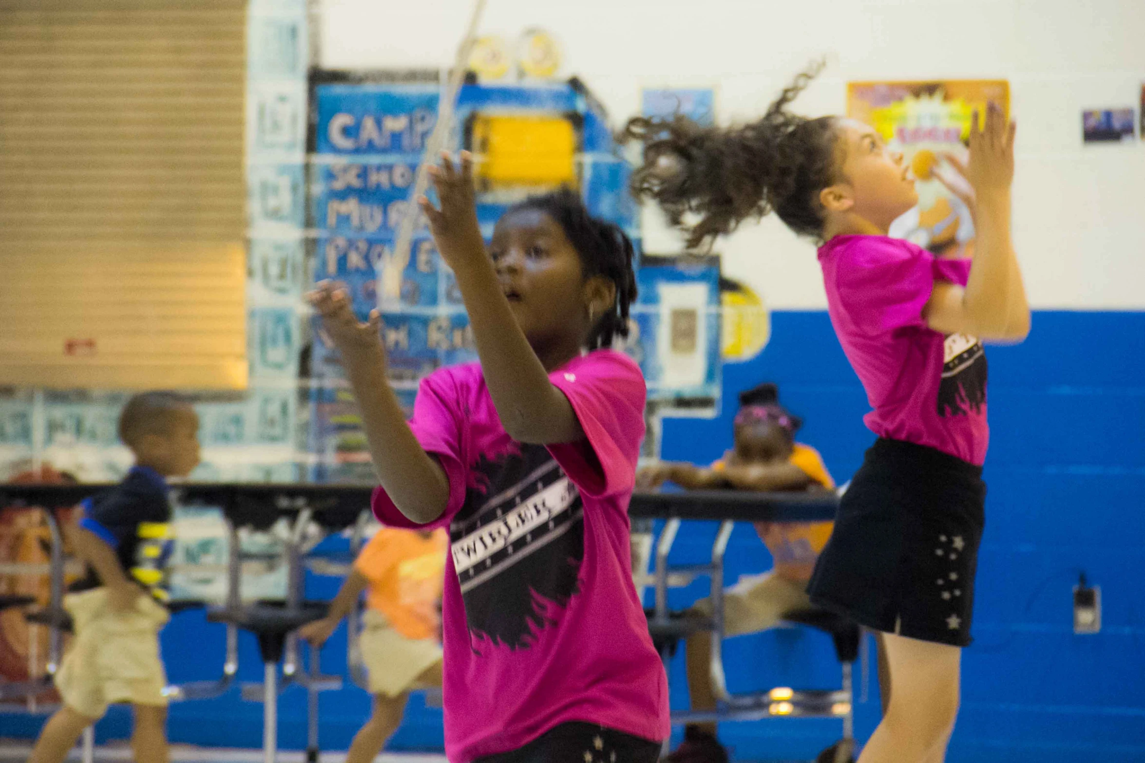 two little girls in pink shirts playing a game of basketball