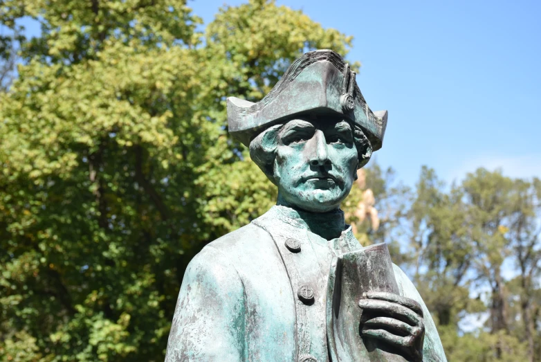 a sculpture of a man wearing a hat and trenchcoat with one hand on his hips