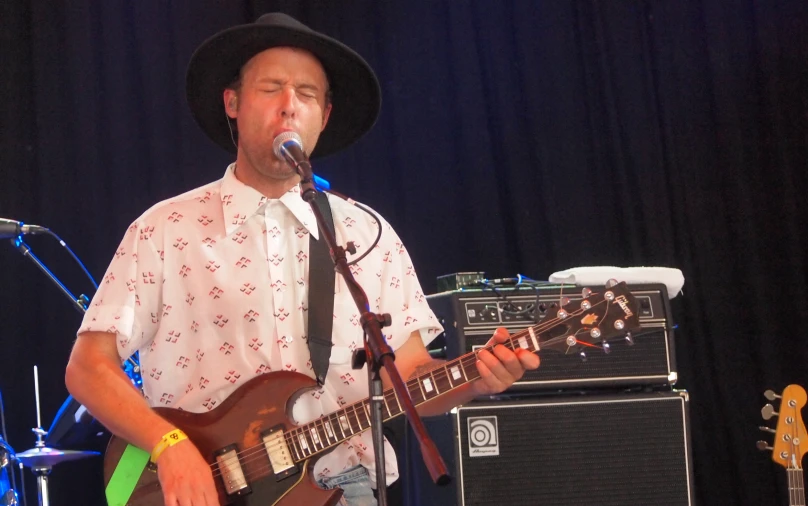 a man in hat playing the guitar on stage