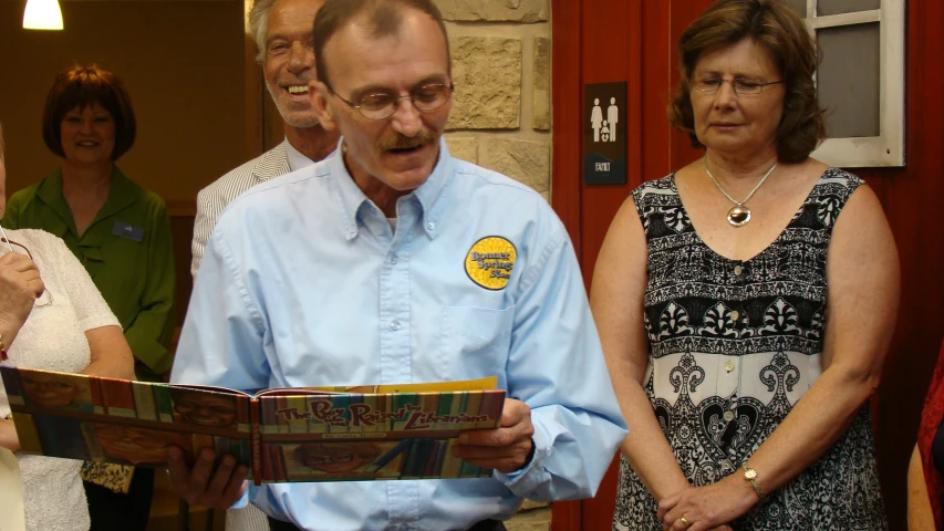 several older people are standing around and looking at papers