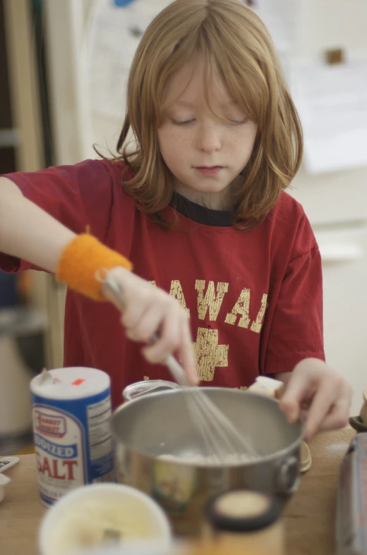 the young child is mixing the food in a pot